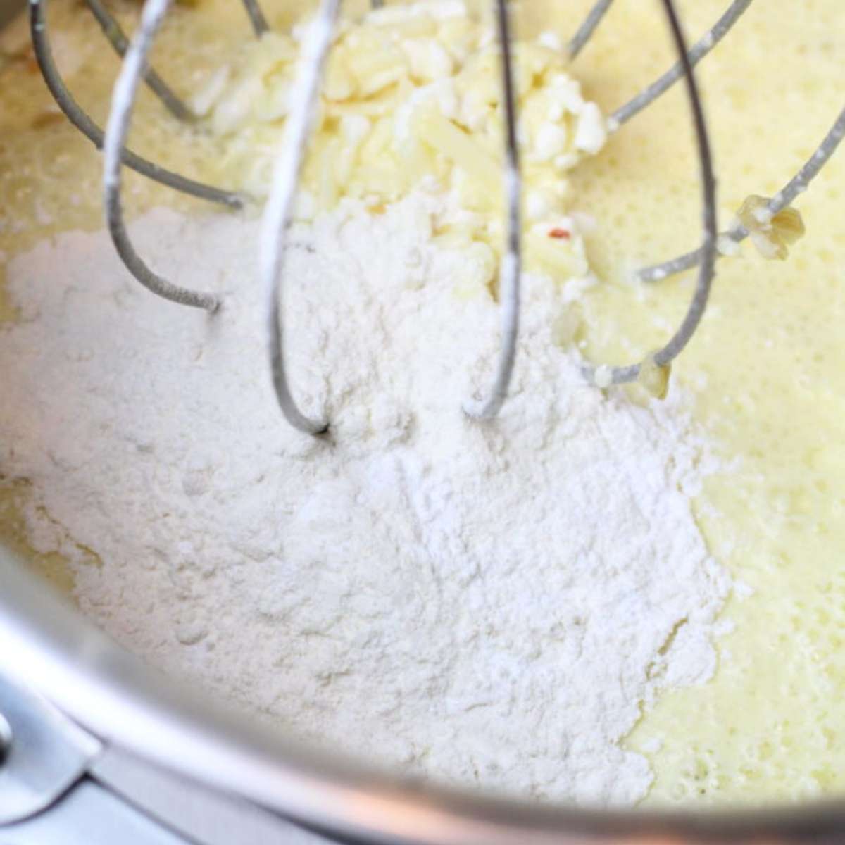 Adding dry ingredients to the mixing bowl of a stand mixer that contains the egg mixture.