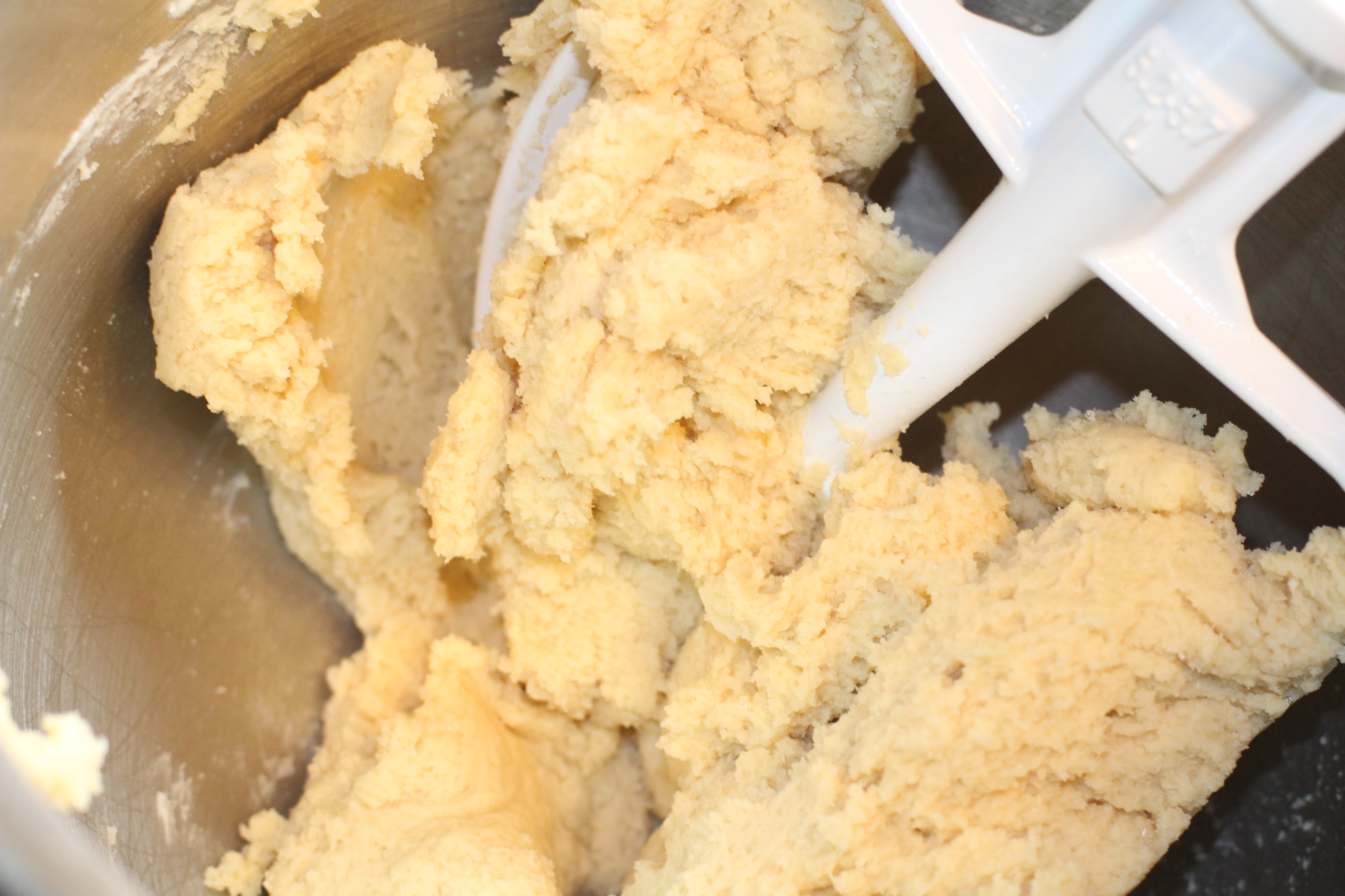 A stand mixer containing beaten sugar shortbread cookie dough.