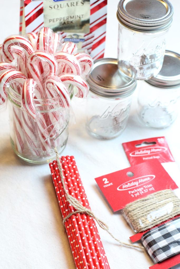 Twine wrapped around a bunch of red paper straws with white polka dots. the straws with be packaged along with candy canes and marshmallows for the hot cocoa mason jar gifts