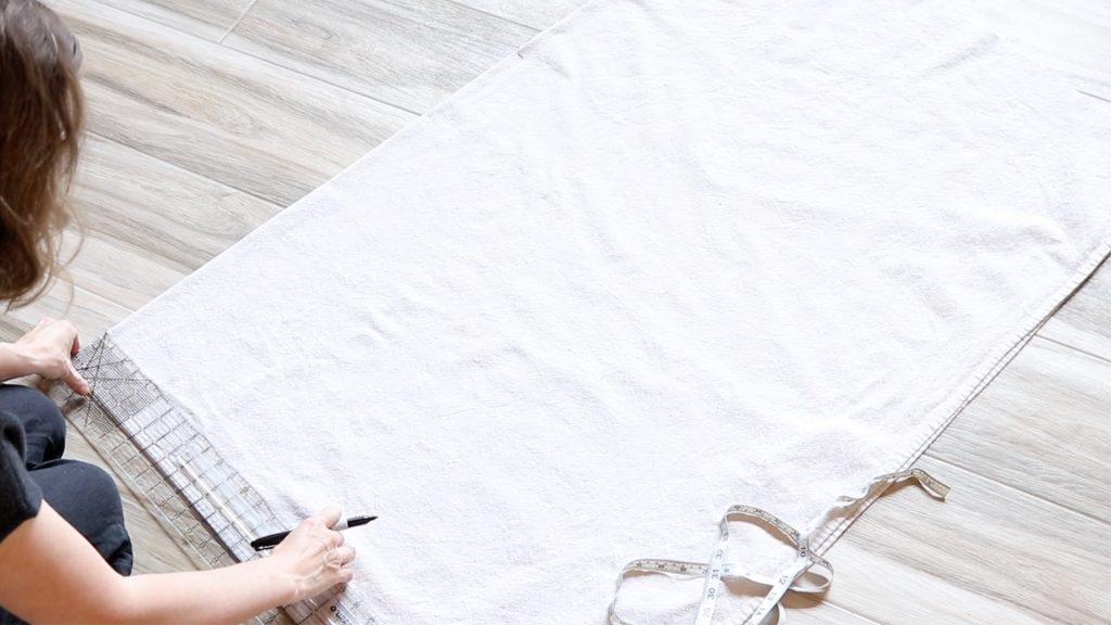 Measuring along the bottom edge of the fabric to prepare for cutting. 