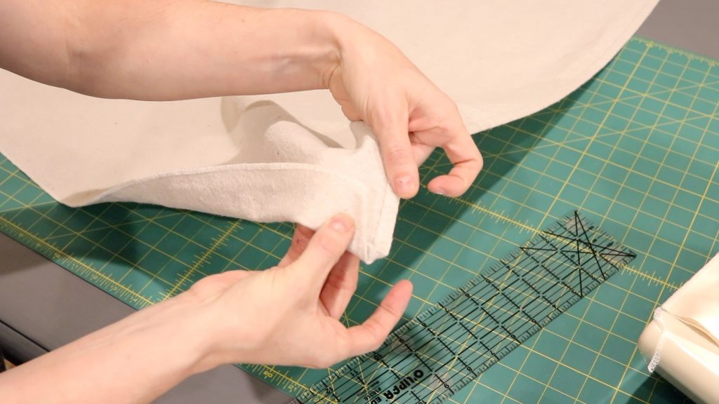 Two hands showing the fabric corner after it has been folded correctly for sewing. 