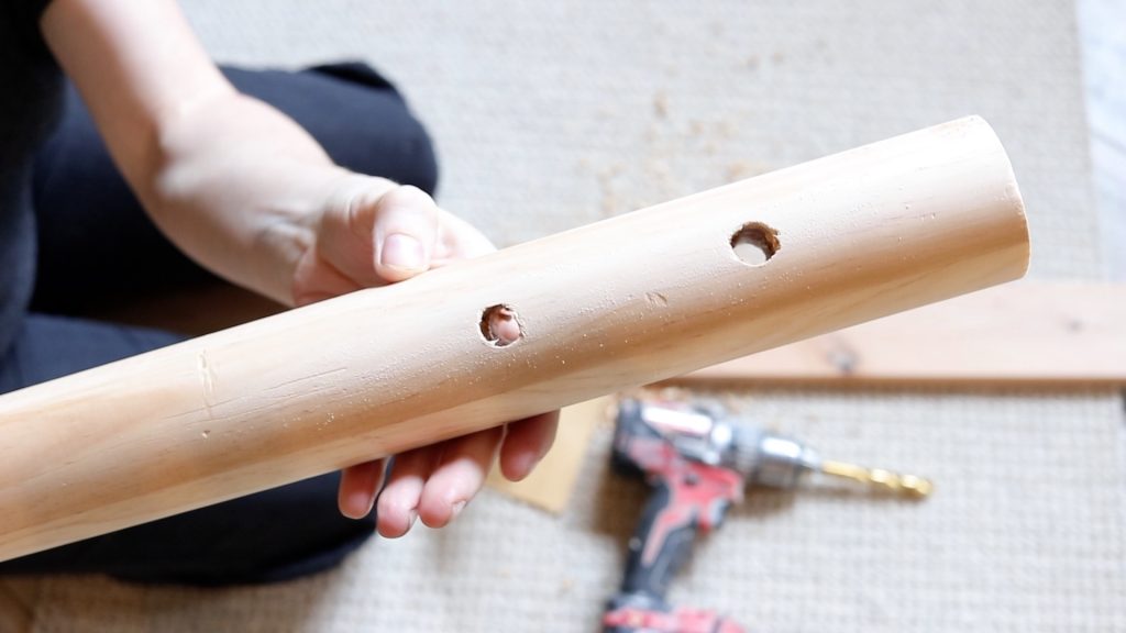 A newly piece of drilled and sanded dowel rod after being prepared to construct a DIy hanging canvas chair.