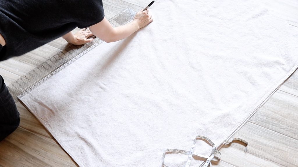 A woman is using a black sharpie marker to mark the canvas before cutting.