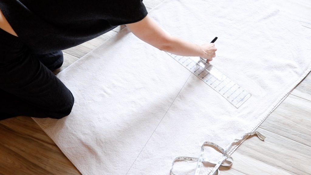 Visible black lines drawn on a piece of cream canvas fabric. 