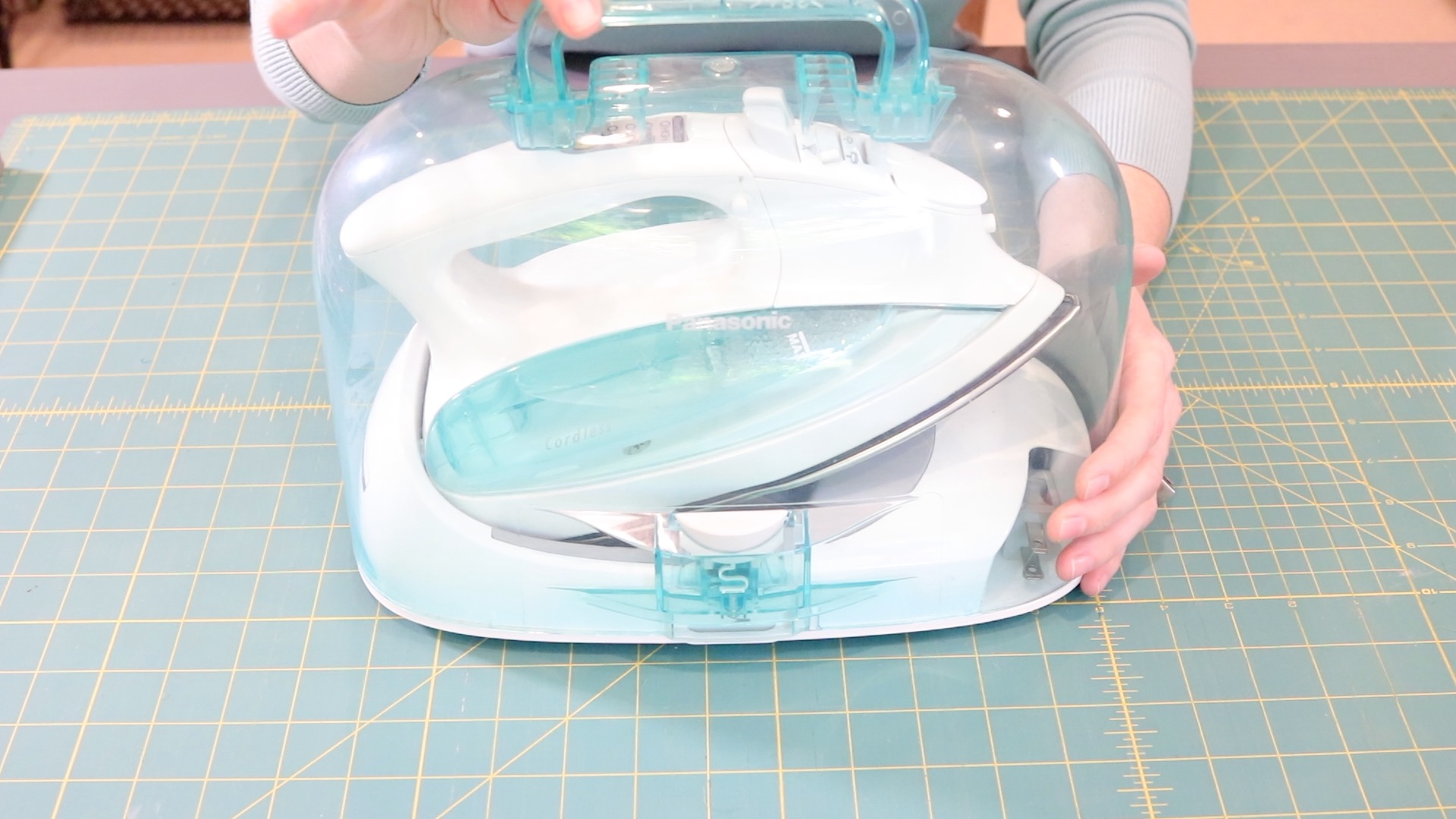 A turquoise cordless, Panasonic iron in a clear plastic case.