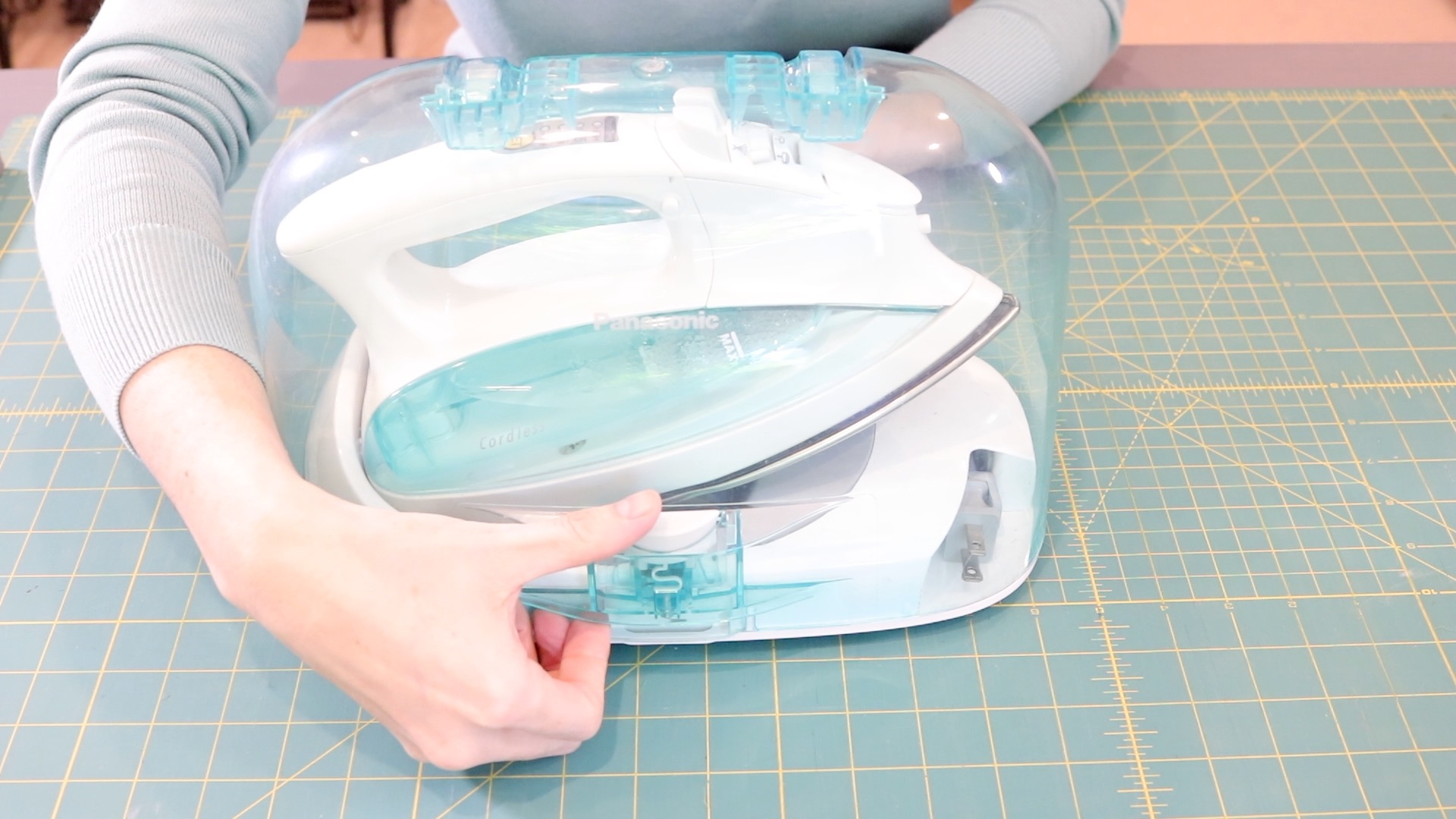 Panasonic cordless iron in a clear plastic case. The case features a carry handle on top.