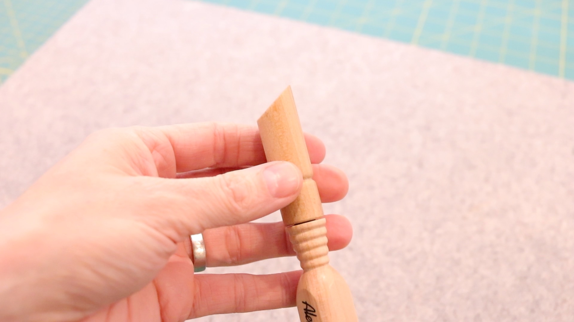 The pressing end of a wooden 4-in-1 sewing tool. 