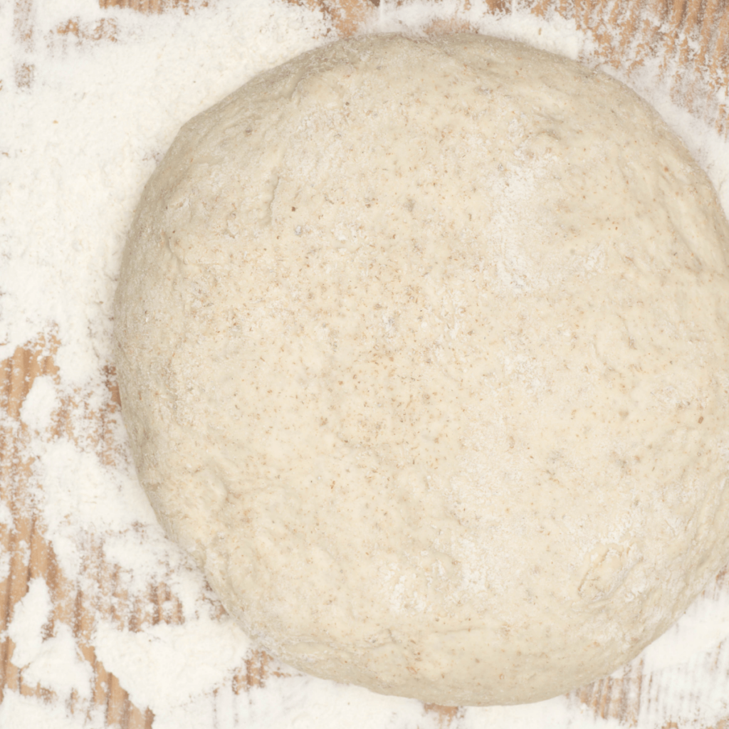 a loaf of sourdough bread on the counter for the first bulk rise. set on a table covered with white flour.