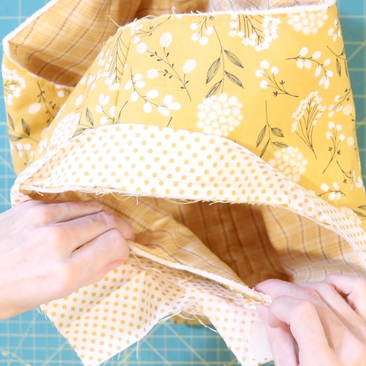 checking the fit of a quilt binding around the edge of a fabric basket to be sure it has been sewn correctly. 