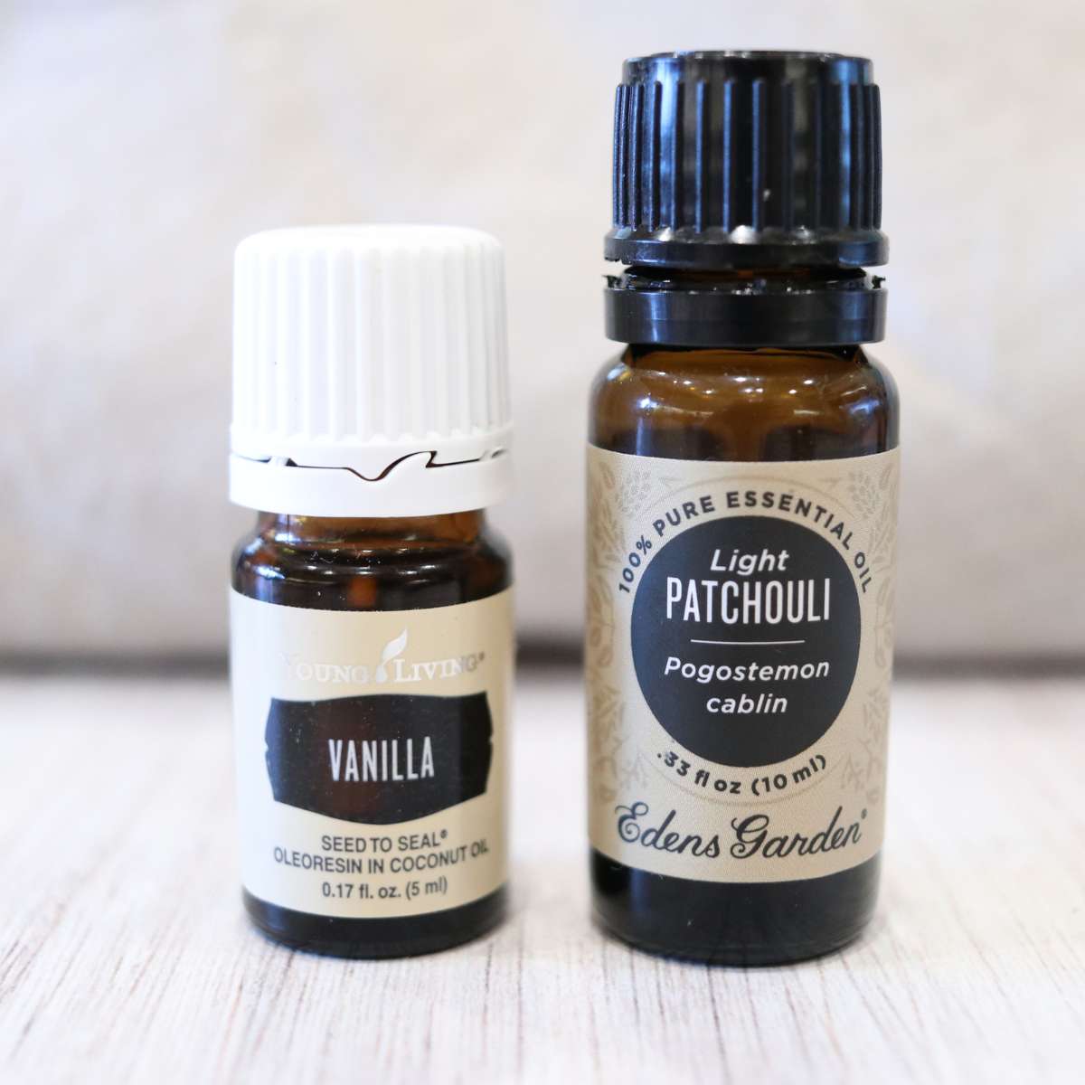 two small bottles of essential oils in amber glass with black tops. Once is vanilla and the other is light patchouli oil. Both are used for a DIY natural deodorant recipe.