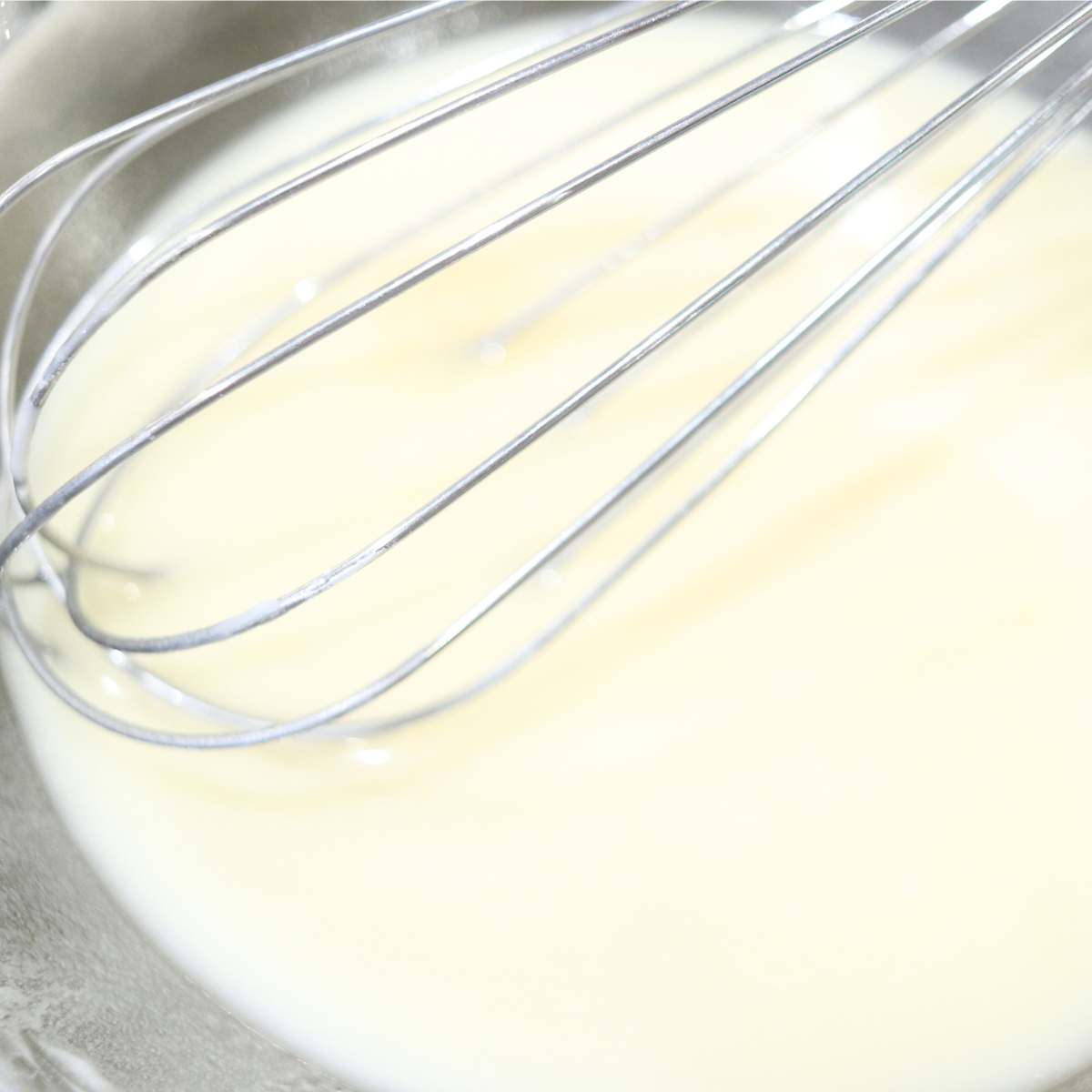 A bowl of melted deodorant ingredients in a clear glass bowl cooling off to be transferred to a small glass storage jar. The liquid is slightly yellow in color.