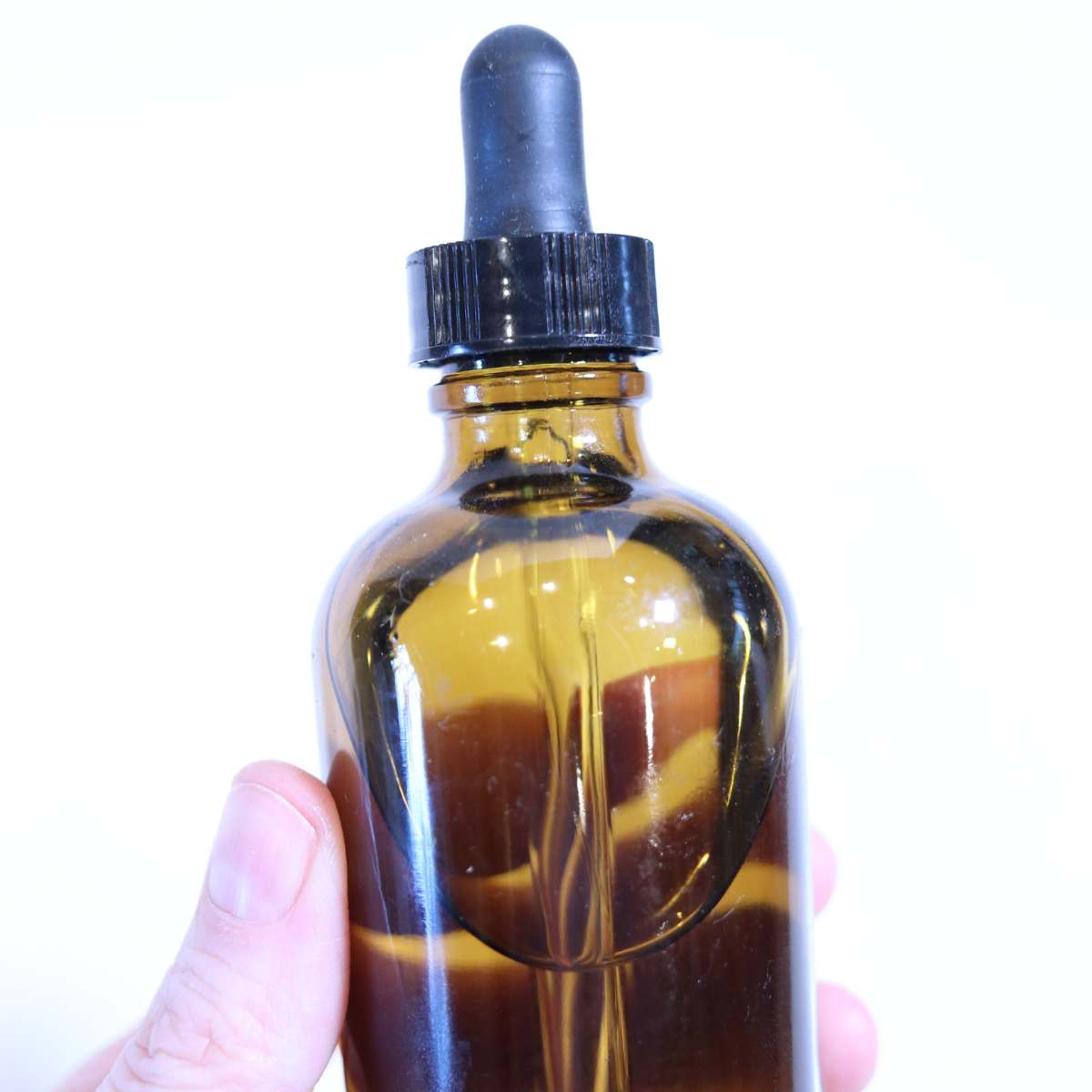 An amber glass bottle with dropper inside full of organic vitamin E oil for DIY skin and beauty recipes.