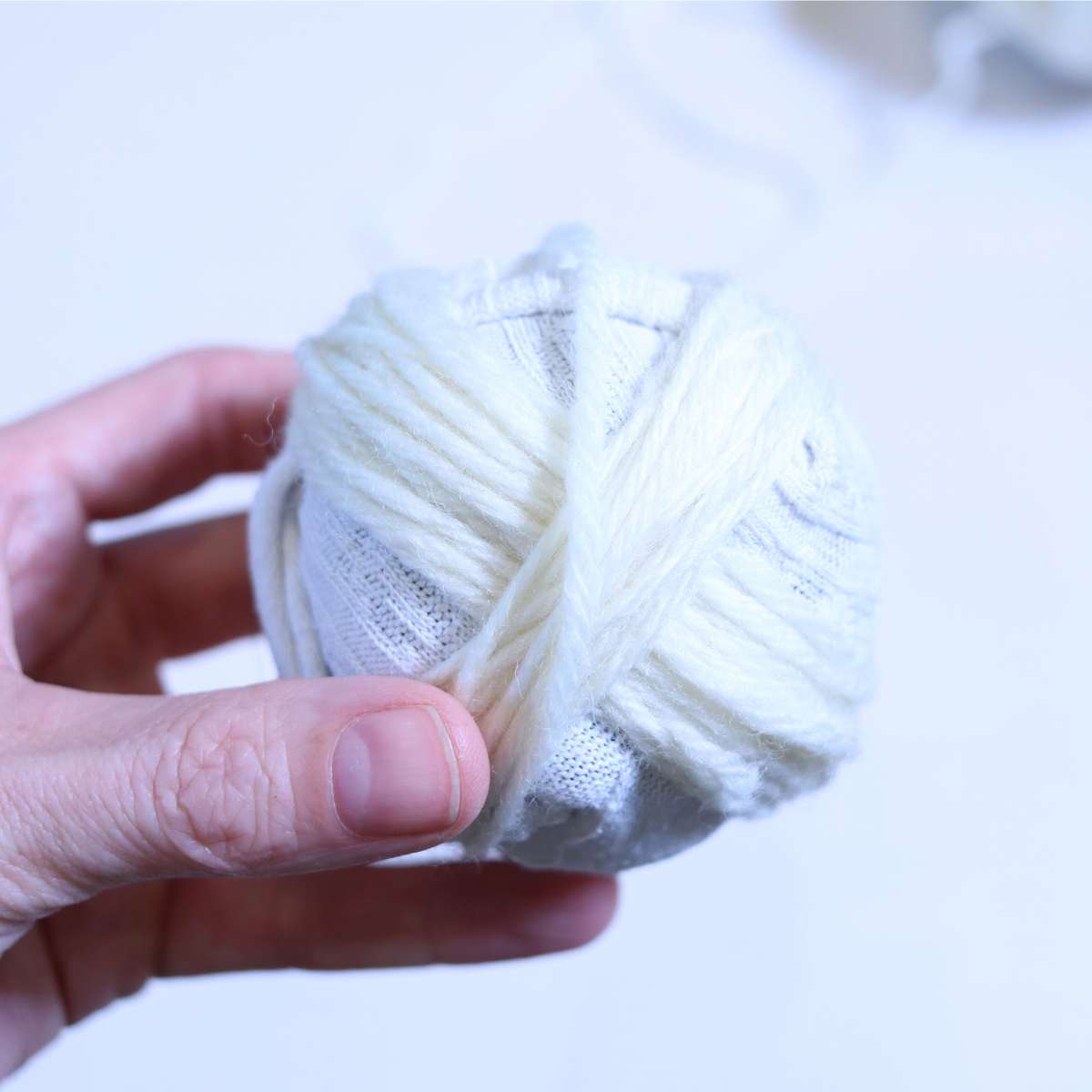 Wrapping the cream colored wool yarn to create a homemade wool dryer ball.
